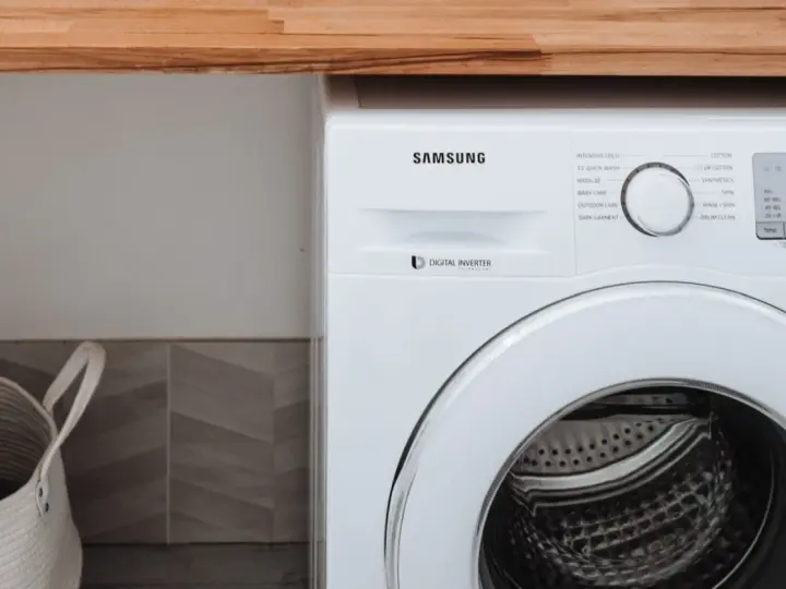 Biała pralka Samsung z technologią Digital Inverter. Obok kosz na pranie.