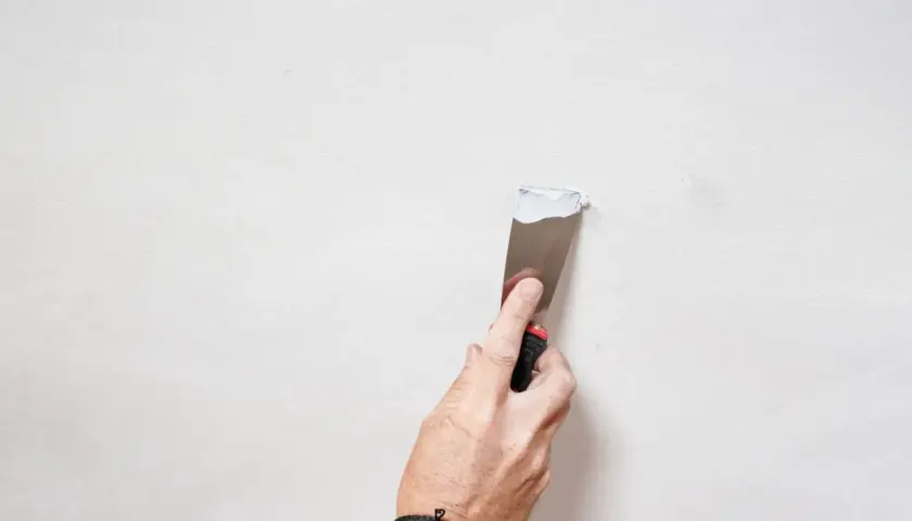 Mano che stende stucco su una parete per la pittura soffitto.