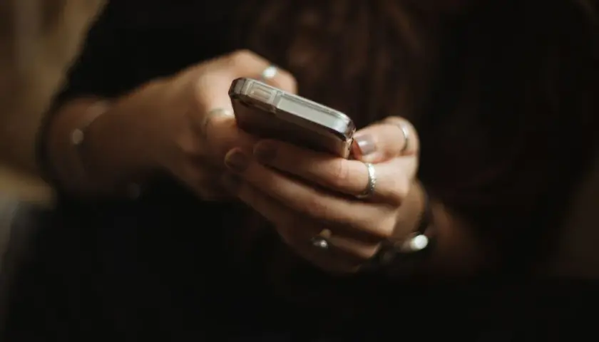 Dłonie z pierścionkami trzymają telefon. Zastanawiasz się paypo co to? To wygodny sposób na płatności online.