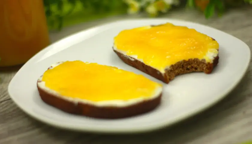 Zwei Scheiben Brot mit Frischkäse und leuchtend gelber, selbstgemachter low carb Marmelade.