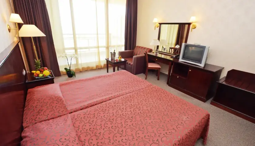 Pokój hotelowy z dwoma łóżkami, owocami, kwiatem i telewizorem. Jakbyś był **gladiola star** w tym miejscu.