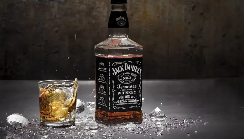 Burbon co to? Butelka Jack Daniel's Tennessee Whiskey i szklanka z drinkiem, lodem i rozbryzgami.