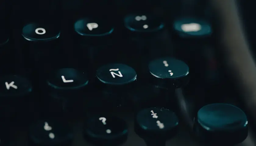 Klawiatura maszyny do pisania, z widocznymi literami i cyframi. Może to być tło dla historii o pomyłkach freudowskich, gdzie przypadkowe naciśnięcie klawisza ujawnia ukryte myśli.
