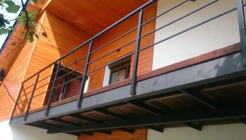 Nowoczesny balkon dostawny z metalową balustradą i drewnianą podłogą. Sprawdź, jaka balkon dostawny cena Cię czeka!