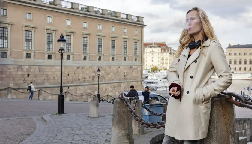 Sara Mac Key, med hörlurar runt halsen, tar en cigarettpaus vid vattnet i Stockholm.