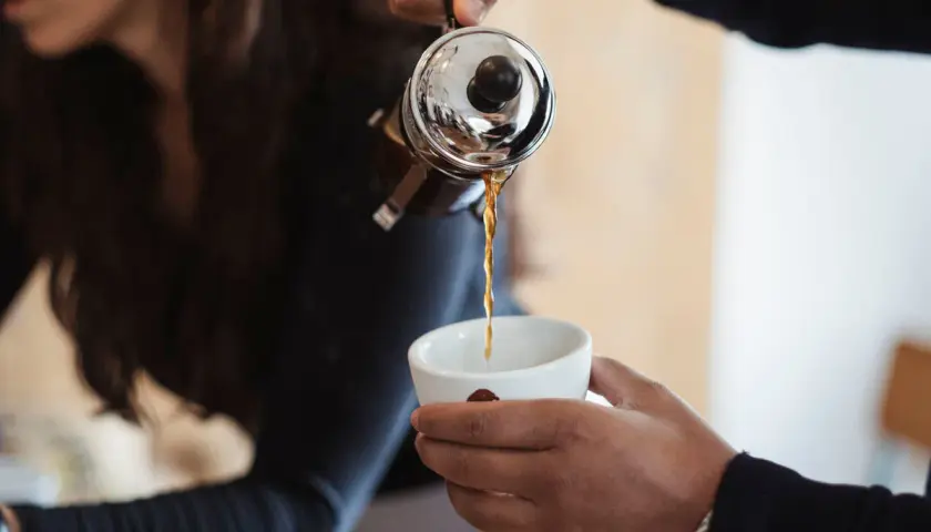Eine French Press wird benutzt, um frisch gebrühten Filterkaffee in eine Tasse zu gießen.