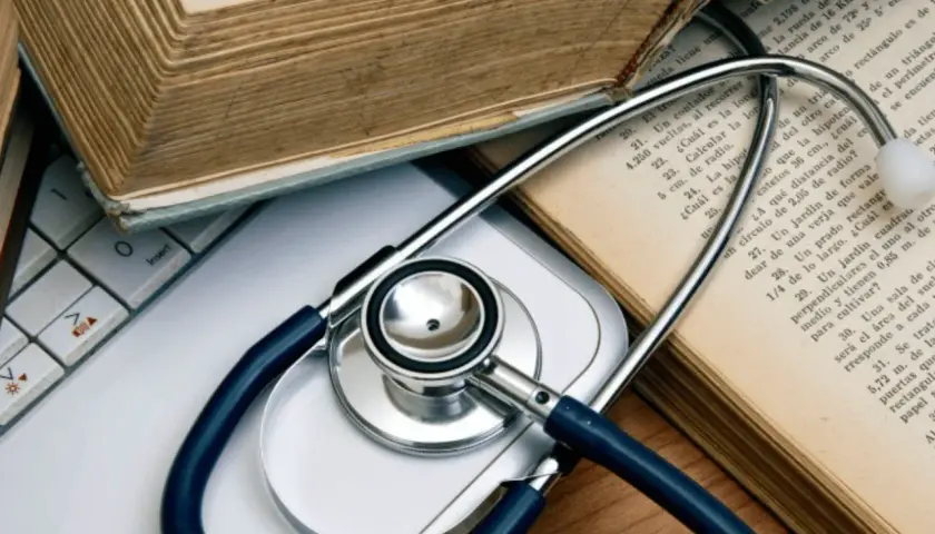 Libri antichi e uno stetoscopio su una tastiera, evocano lo studio della medicina legale.
