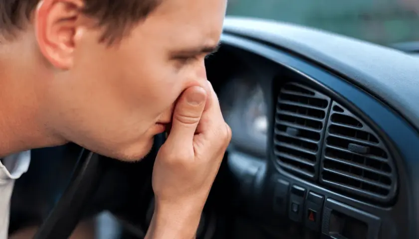 Man håller för näsan i bilen, en tydlig signal att det är dags att ta bort dålig lukt i bil.