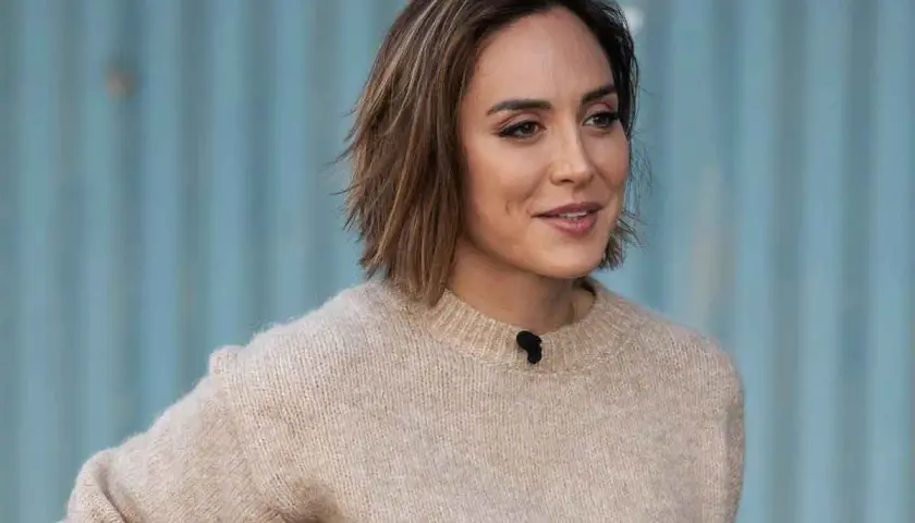 Mujer con un moderno corte pelo bob capas, luciendo un suéter beige y una sonrisa.
