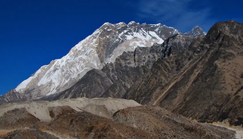 Majestatyczny Mount Everest w śnieżnej koronie, widok z bazy pod Everestem. Surowe, skaliste zbocza i błękitne niebo.