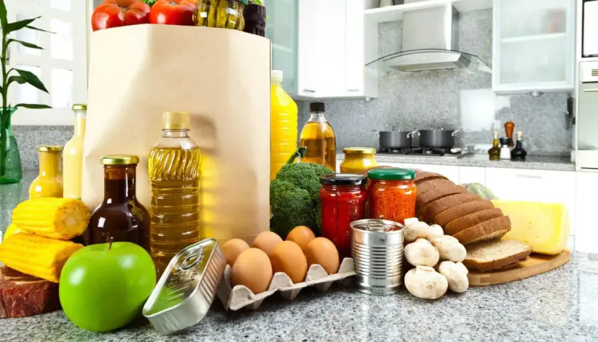 Un sacco di carta pieno di pomodori, uova, pane, formaggio e altri cibi proteici, pronti per essere cucinati.