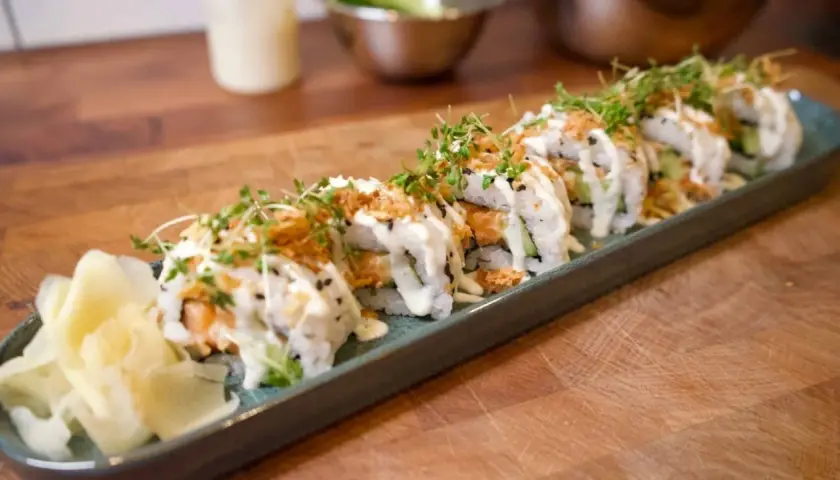 En rad läckra sushirullar med lax och gurka, toppade med majonnäs och krispiga lökar. Ett perfekt sushi recept för hemmakockar.