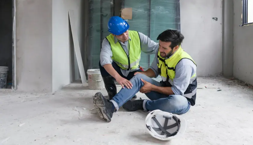Operaio ferito assistito da un collega. La scena evoca la necessità di un risarcimento per morte sul lavoro o infortunio grave.