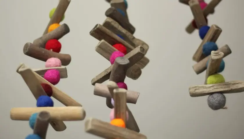 Bunte Filzkugeln und Holzstücke hängen an Schnüren. Tolle nadelfilzen ideen für Deko oder Vogelfutter.
