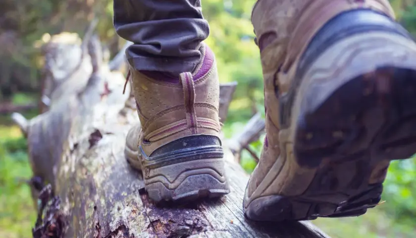 Osoba w butach trekkingowych stąpa po powalonym drzewie. Czy buty trekkingowe powinny być większe? Wygoda to podstawa na szlaku.