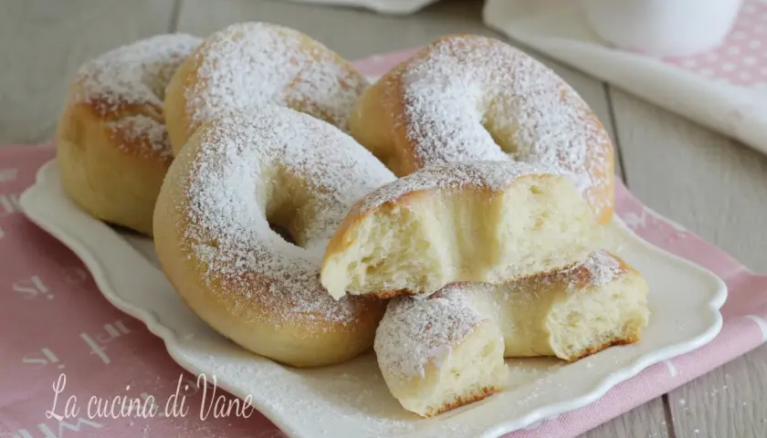Ciambelle al forno soffici e profumate, cosparse di zucchero a velo. Una delizia per la colazione o la merenda.