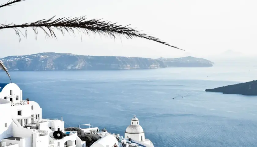 Santorini, Grecja. Białe domy na klifie, błękitne morze i wyspy w oddali. Ciekawe miejsca i widoki.