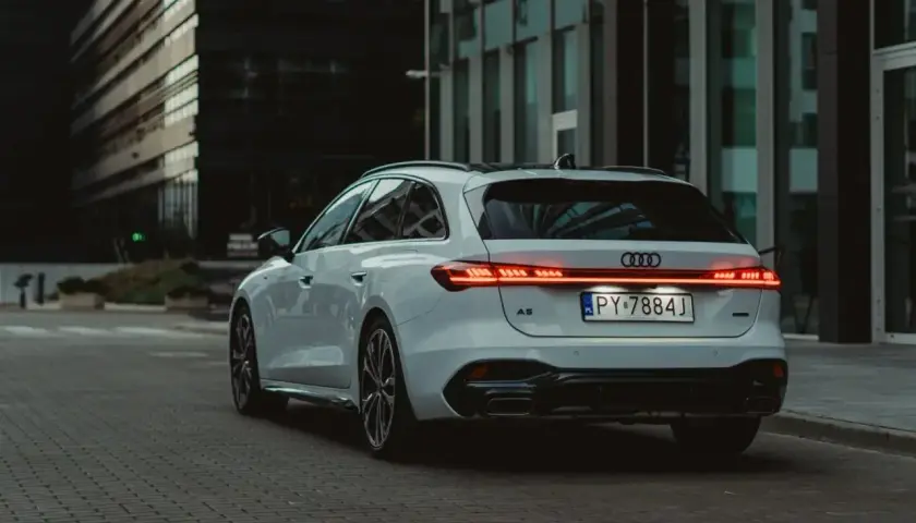 Białe Audi A5 Avant 2025 z nowoczesnymi światłami LED na tle miejskiej architektury.