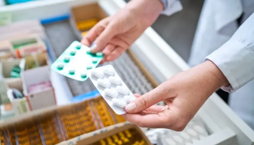 Farmaceuta wybiera opakowanie tabletek, być może zawierających doloxib, z szuflady aptecznej.