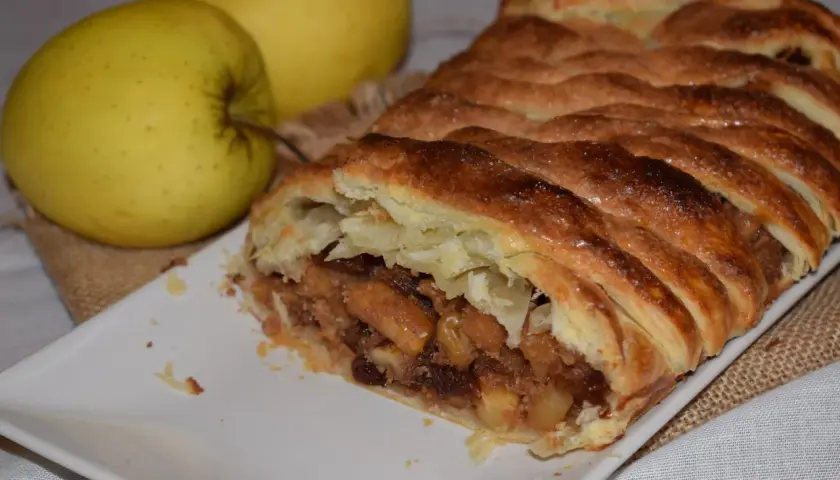 Strudel de manzana con hojaldre dorado y crujiente, relleno de trozos de manzana y pasas. ¡Perfecto para tu próxima receta!