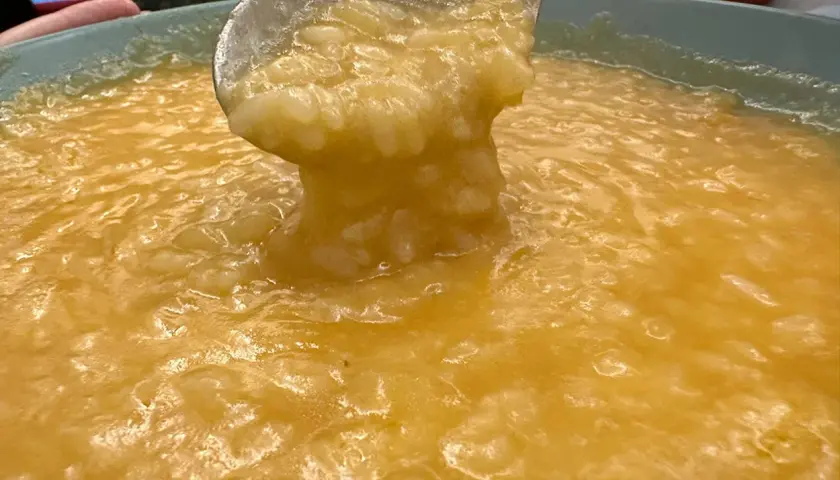 Un mestolo solleva una porzione cremosa di riso e patate, un comfort food caldo e invitante.