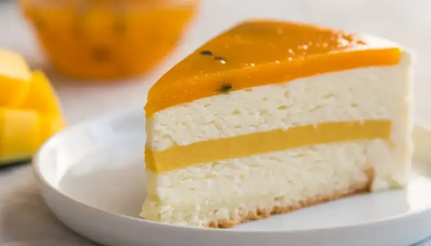 Pyszny kawałek tortu z warstwami białego kremu i żółtym musem mango, zwieńczony galaretką z mango.