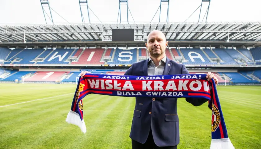 Artur Skowronek z szalikiem Wisły Kraków na tle stadionu. "Jazda! Wisła Kraków! Biała Gwiazda!" - krzyczy kibic.