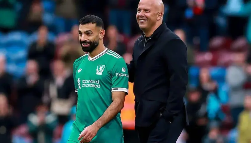 Piłkarz Liverpoolu w zielonej koszulce i łysy mężczyzna w czarnej kurtce uśmiechają się. To może być moment po udanych transferach Liverpoolu.