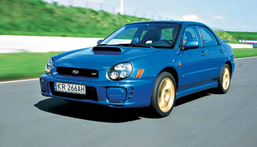 Niebieskie, małe szybkie auto Subaru Impreza WRX STI pędzi po torze wyścigowym.