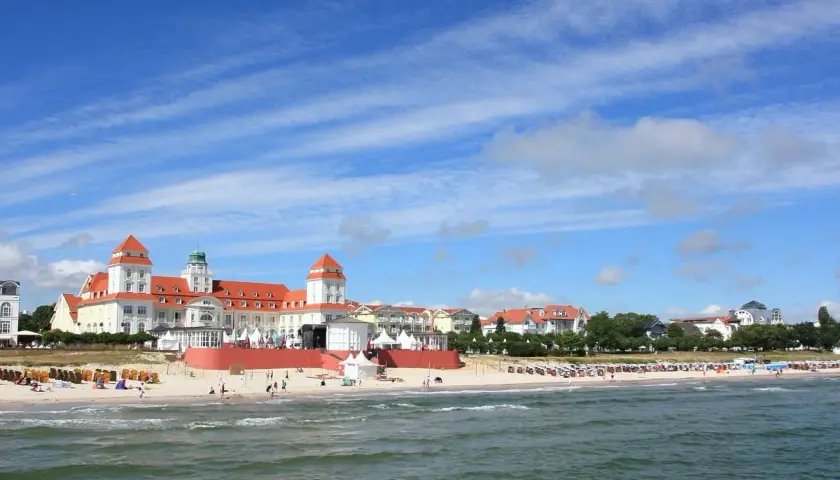 Prachtvolles Gebäude am Strand des Ostseebad Binz, mit roten Dächern und Türmen, unter blauem Himmel mit Wolken.