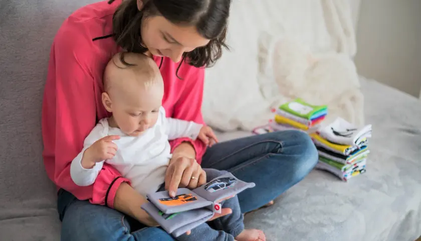 Mama z dzieckiem czyta książeczkę o samochodach. To idealny urlop na dziecko, pełen wspólnych chwil i nauki.