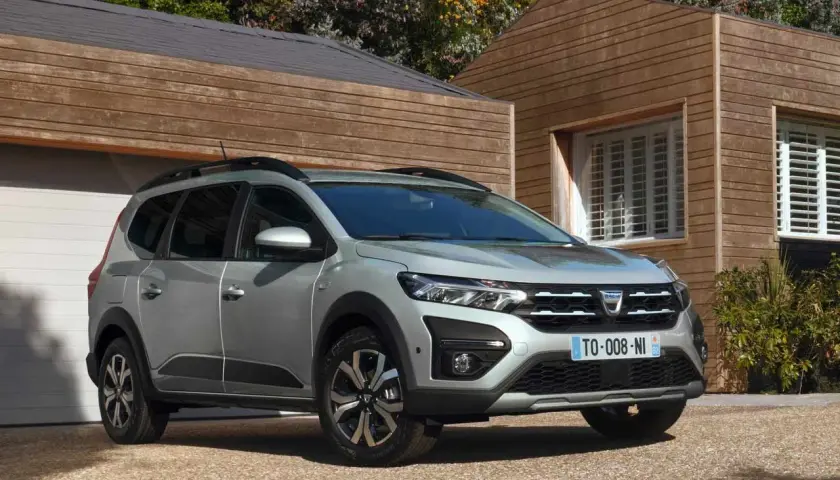 Dacia Jogger grigio metallizzato, un'auto che consuma meno GPL, parcheggiata davanti a una casa moderna in legno.