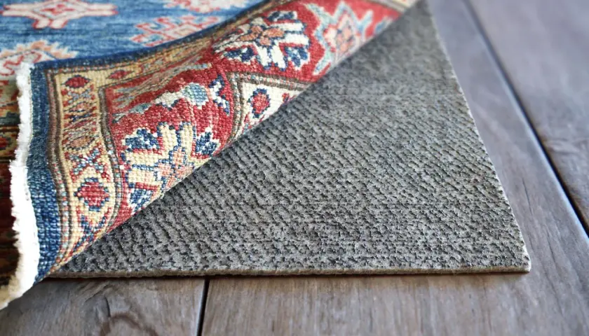 A rug is flipped to reveal its backing, showing how to waterproof a rug with a protective layer.