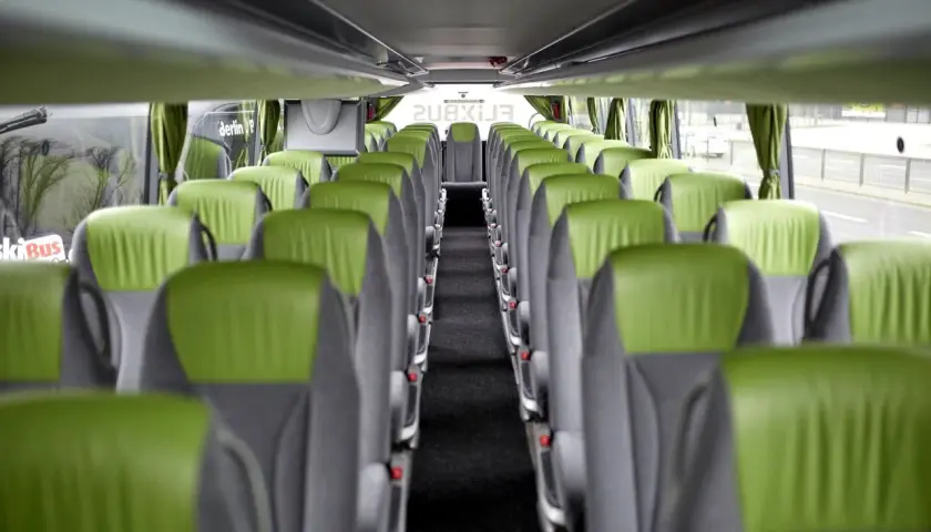 Wnętrze autokaru FlixBus, zielone siedzenia tworzą pusty korytarz. Idealne miejsce na podróż.