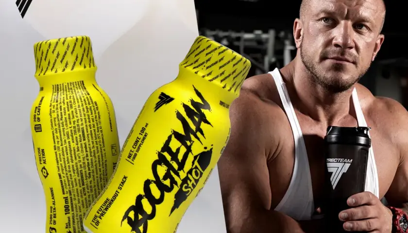 Mężczyzna z potężną sylwetką trzyma shaker, obok niego żółte shoty "Boogieman Shot" - napój dla sportowców.