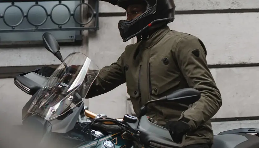 Motociclista con casco y chaqueta de aventura, que es Gore-Tex, lista para el viaje.