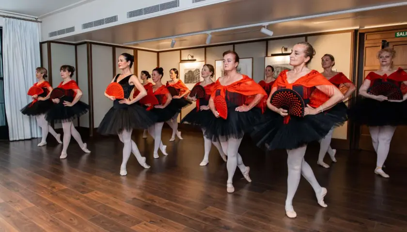 Donne in abiti da balletto nero e rosso, con ventagli, pronte a fare danza.