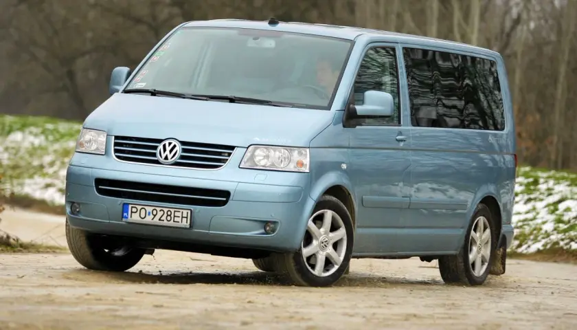 Jasnoniebieski Volkswagen Transporter T5 na drodze gruntowej.