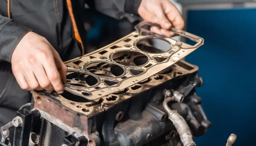 Meccanico posiziona una nuova guarnizione della testata su un motore. Scopri quanto costa cambiare la guarnizione della testata.