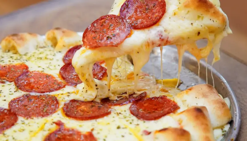Pizza de pepperoni con queso mozzarella derretido y estirándose.