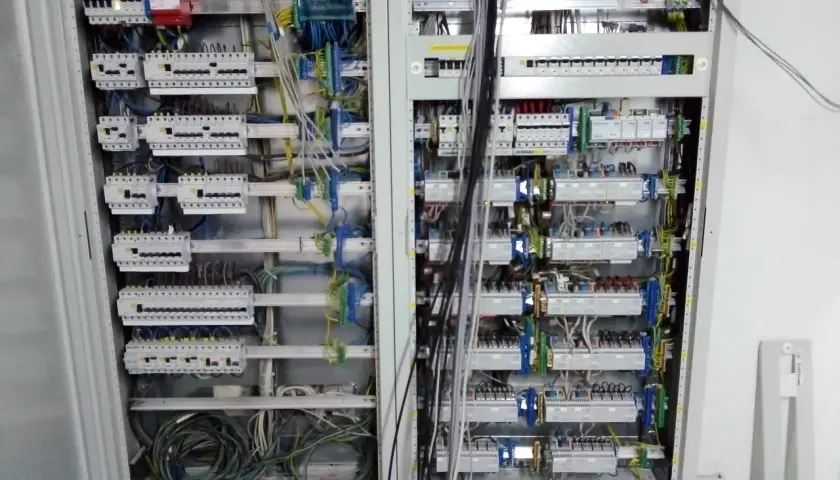 Otwarta skrzynka elektryczna z licznymi przewodami i bezpiecznikami.