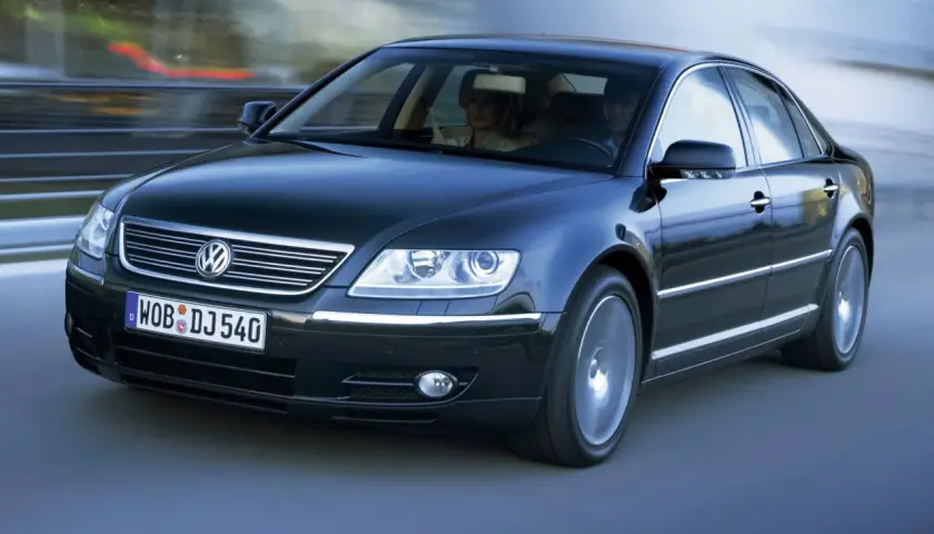 Elegancki, czarny Volkswagen Phaeton w ruchu, z parą pasażerów w środku.