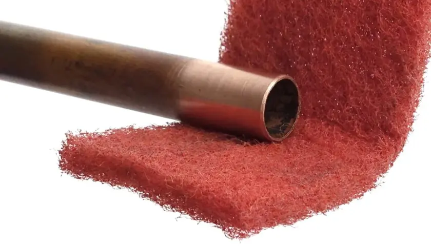 Miedziana rura przygotowana do lutowania aluminium z miedzią, na czerwonej druciance.