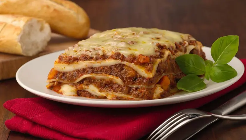 Herzhafte Lasagne mit Hackfleisch und Käse, dazu Baguette. Welcher Wein zu Lasagne passt, ist eine Frage des Geschmacks, aber ein kräftiger Rotwein ist oft ideal.