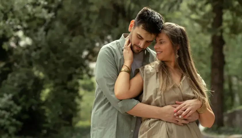 Coppia abbracciata in un parco, un momento di tenerezza che racchiude il vero amore significato.