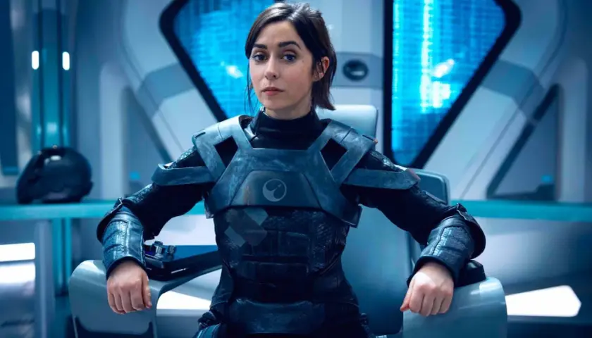Une femme en armure futuriste, assise dans un cockpit, pourrait être un personnage de Black Mirror saison 7.