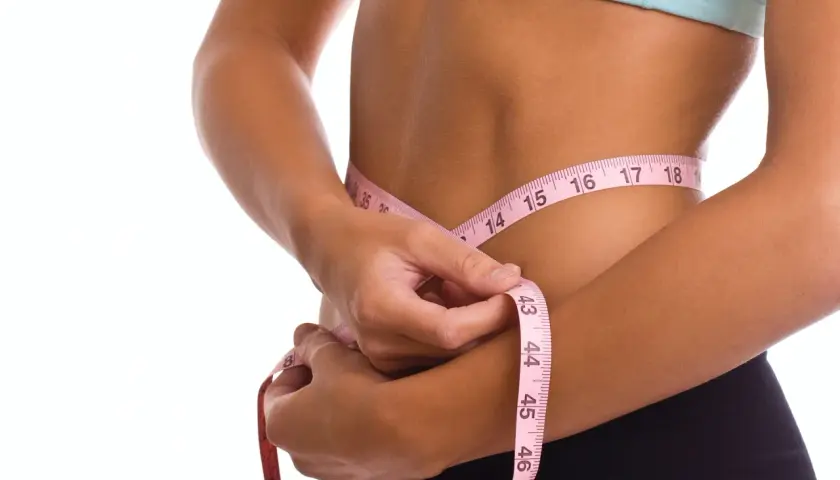 Kobieta mierzy talię centymetrem. Efekty diety 1300 kcal są widoczne.