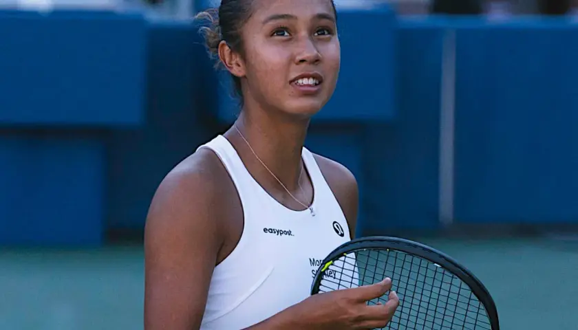 Leylah Fernandez, młoda tenisistka, z rakietą w dłoni, patrzy w górę z determinacją na twarzy.