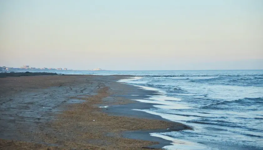 Plaża nad morzem Kaspijskim, które wysycha. W oddali widać zabudowania.