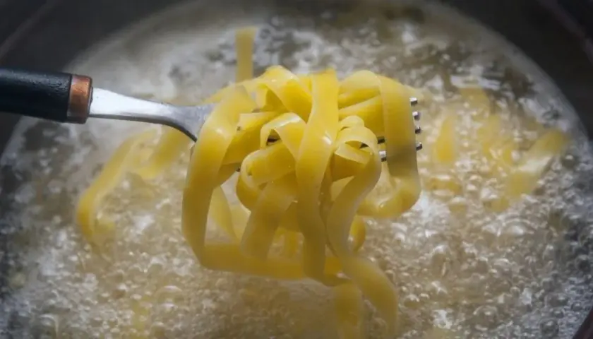Tagliatelle na widelcu unoszone z wrzącej wody. Prosty sposób, jak ugotować makaron idealnie al dente.